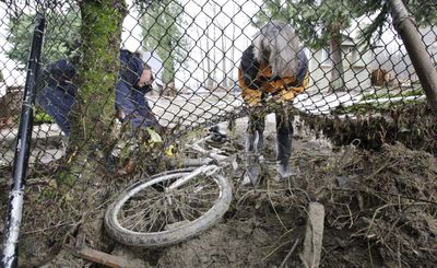 Annette Pole, left, and Corliss Serka work Monday to free a bicycle caught in a fence in front of Serka’s flood-ravaged home  in Carnation, Wash.  (Associated Press / The Spokesman-Review)