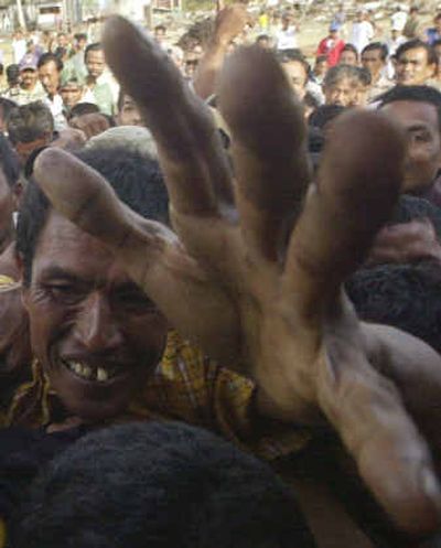 
Survivors scramble to get food and other supplies being unloaded from a U.S. Navy Sea Hawk helicopter. 
 (Associated Press / The Spokesman-Review)