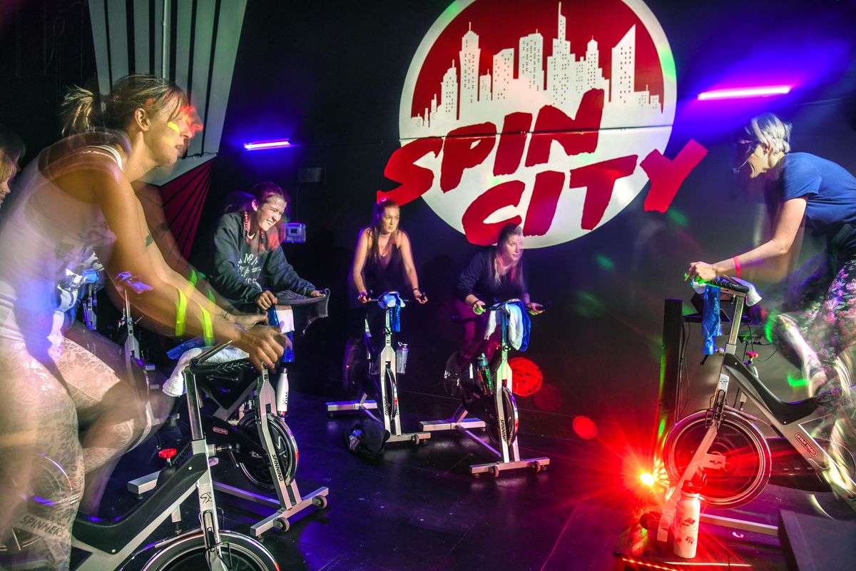 Anna Steele, indoor cycling instructor, right, leads a spin class under black light on Jan. 8 at Spin City. (Dan Pelle / The Spokesman-Review)