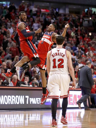 Wizards John Wall and Bradley Beal celebrate 101-99 win as Bulls’ Kirk Hinrich walks off the court after missing two free throws. (Associated Press)