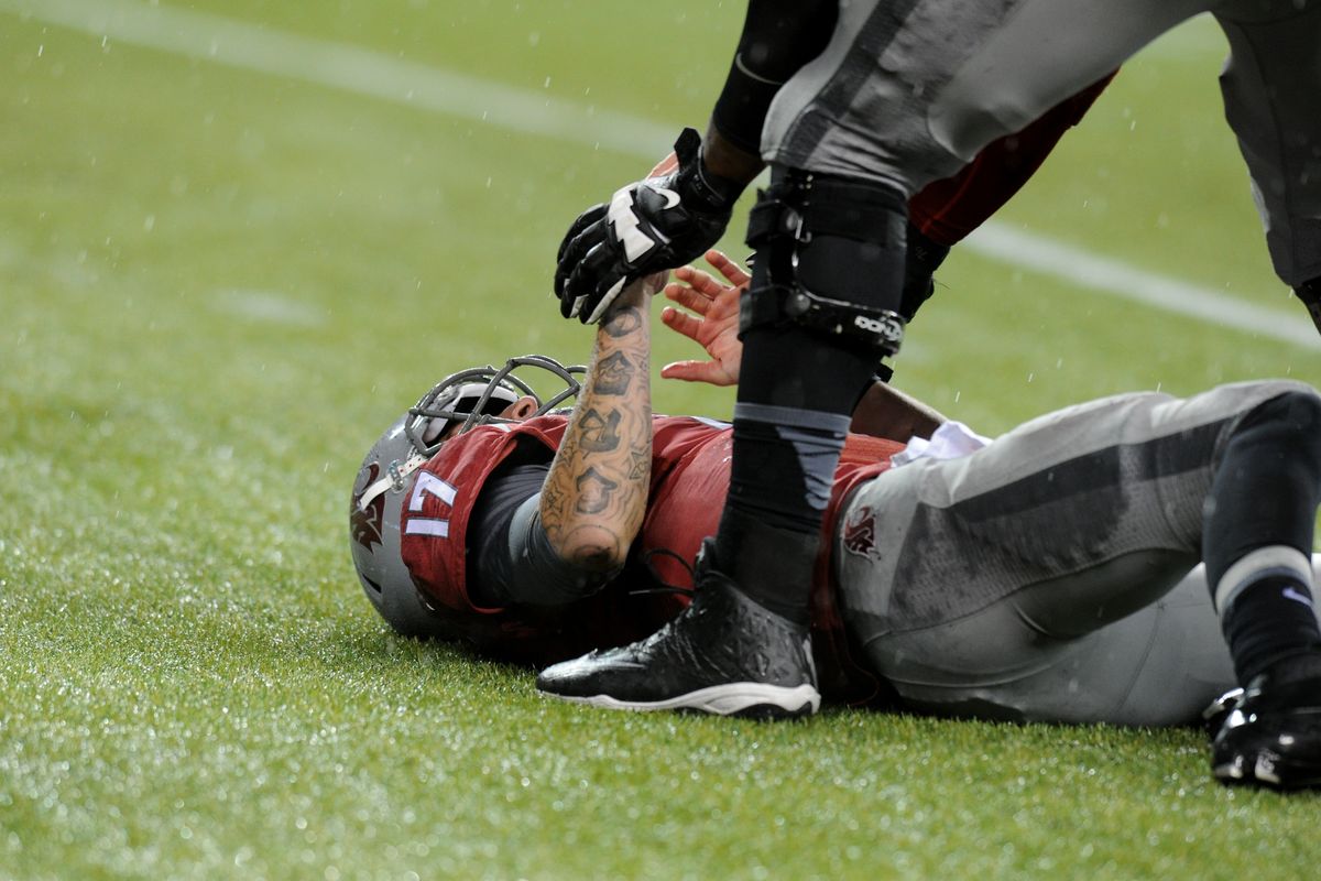 Washington State backup quarterback Austin Apodaca gets a helping hand after being sacked on Saturday. (Tyler Tjomsland)