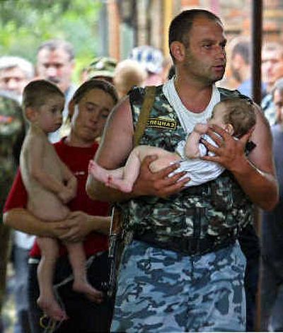 
A special forces soldier carries a baby and a woman carries a child after being released by militants Thursday. 
 (Associated Press / The Spokesman-Review)