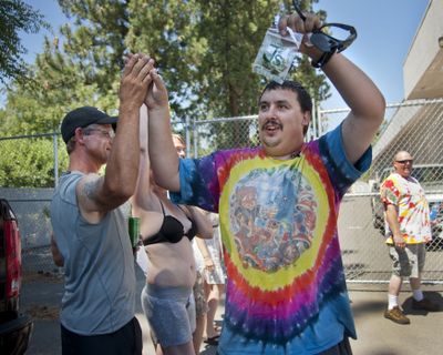 Mike Boyer walks through a crowd showing off his legal pot purchase from Spokane Green Leaf on July 8, 2014. (File)