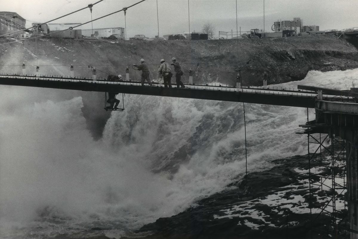 Workmen labor in frigid temperatures in February 1974 to finish a pair of suspension bridges linking Havermale and formerly named Crystal Island, and the north and south banks of the river.  (Jim Shelton/THE SPOKESMAN-REVIEW)
