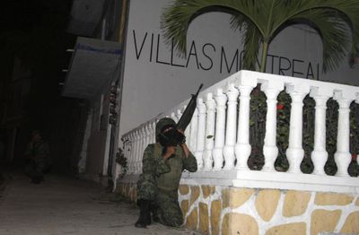 A soldier holds position during a gunfight in Acapulco, Mexico, on Saturday. Sixteen gunmen and two soldiers died in the fighting. (Associated Press / The Spokesman-Review)