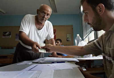 
A member of Hezbollah gives U.S. currency  Friday to a Lebanese man who lost his house during the monthlong Israeli offensive.   The exchange took place at a school in Bourj el-Barajneh, a southern suburb of Beirut. . 
 (Associated Press / The Spokesman-Review)