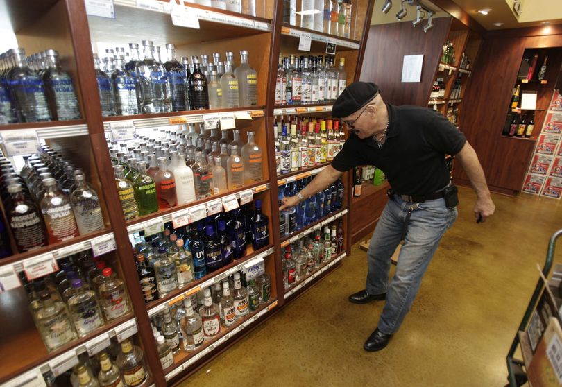 John TaJalle, of Federal Way, Wash., compares bottles of lower-priced gin as he shops in a Washington state liquor store in Seattle.  (Associated Press)