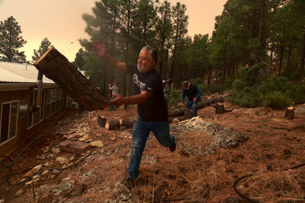 Chris Castillo throws a freshly-cut log as he and his cousins clear a wireline along a family member