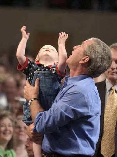 
President Bush looks up at the lights with a child he picked from the crowd Saturday during a stop at the Canton Civic Center in Canton, Ohio. 
 (Associated Press / The Spokesman-Review)