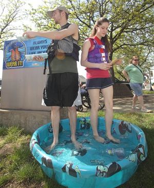In this Saturday, May 21, 2011 photo, Bruce Crawford and Grace Nash pass out water safety brochures at the International Cuisine Festival in Painesville, Ohio. A judge sentenced the pair to stand in a tiny swimming pool while wearing life jackets and handing out the brochures in lieu of jail time, after searchers spent hours looking for them last month after they were spotted on the Grand River and they lied to an official about being in the water.  ((AP Photo/The News-Herald, Michael Allen Blair))