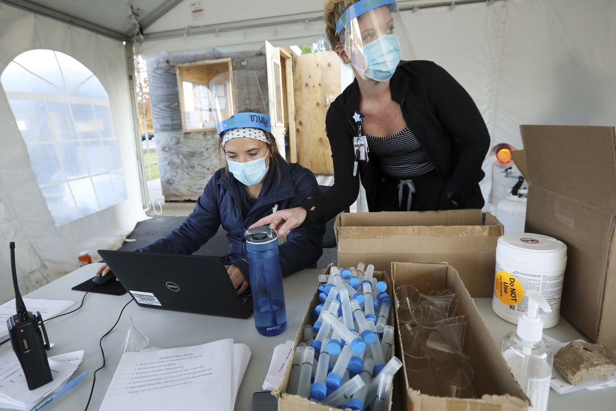 Nursing assistant Monica Brodsky, left, and nurse Taylor Mathisen work at a drive-thru testing site for COVID-19 in the parking lot at UW Health Administrative Office Building in Middleton, Wis., Monday, Oct. 5, 2020. A surge of coronavirus cases in Wisconsin and the Dakotas is forcing a scramble for hospital beds and raising political tensions, as the Upper Midwest and Plains emerge as one of the nation’s most troubling hotspots.  (AMBER ARNOLD)
