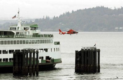 
A U.S. Coast Guard helicopter flies low near a ferry  Friday while searching for debris from the Thursday night crash of a medical transport helicopter near Edmonds, Wash. 
 (Associated Press / The Spokesman-Review)