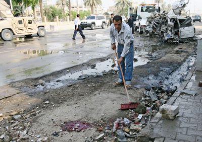 A man sweeps following a suicide car bomb  in Bab al-Sharji area.  (Associated Press / The Spokesman-Review)
