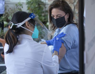 Nancy Butner, NW Division VP for Life Care Center is vaccinated by Kristine Kim, a pharmacist for CVS outside of the Center in Kirkland, Wash., on Dec. 28. Residents and staff at Yakima-area long-term care centers received their first COVID-19 vaccines this week.  (Associated Press)