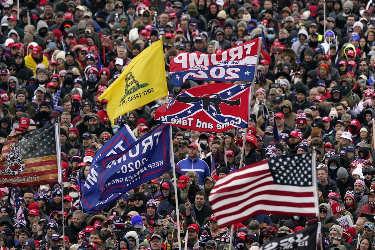 Supporters listen as President Donald Trump speaks as a Confederate-themed and other flags flutter in the wind during a Jan. 6, 2021, rally in Washington. War-like imagery has begun to take hold in mainstream Republican political circles in the wake of the deadly attack on the U.S. Capitol, with some elected officials and party leaders rejecting calls to tone down their rhetoric contemplating a second civil war.  (Evan Vucci)