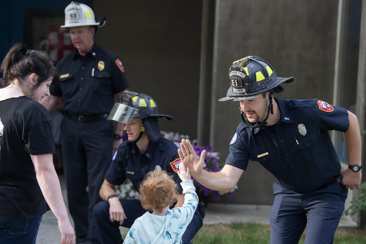 Firefighter Trevor Richards, right, along with other Spokane firefighters, welcomes students and their younger siblings to the first day of school, Thursday, Aug. 30, 2018, at Roosevelt Elementary in Spokane. (Jesse Tinsley / The Spokesman-Review)