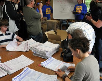 Workers for the Secretary of State’s Elections Division count petitions for Initiative 1125 on Friday while sponsor Tim Eyman holds a press conference about the proposal. The workers had to stop while Eyman was talking to keep from losing count. (Jim Camden)
