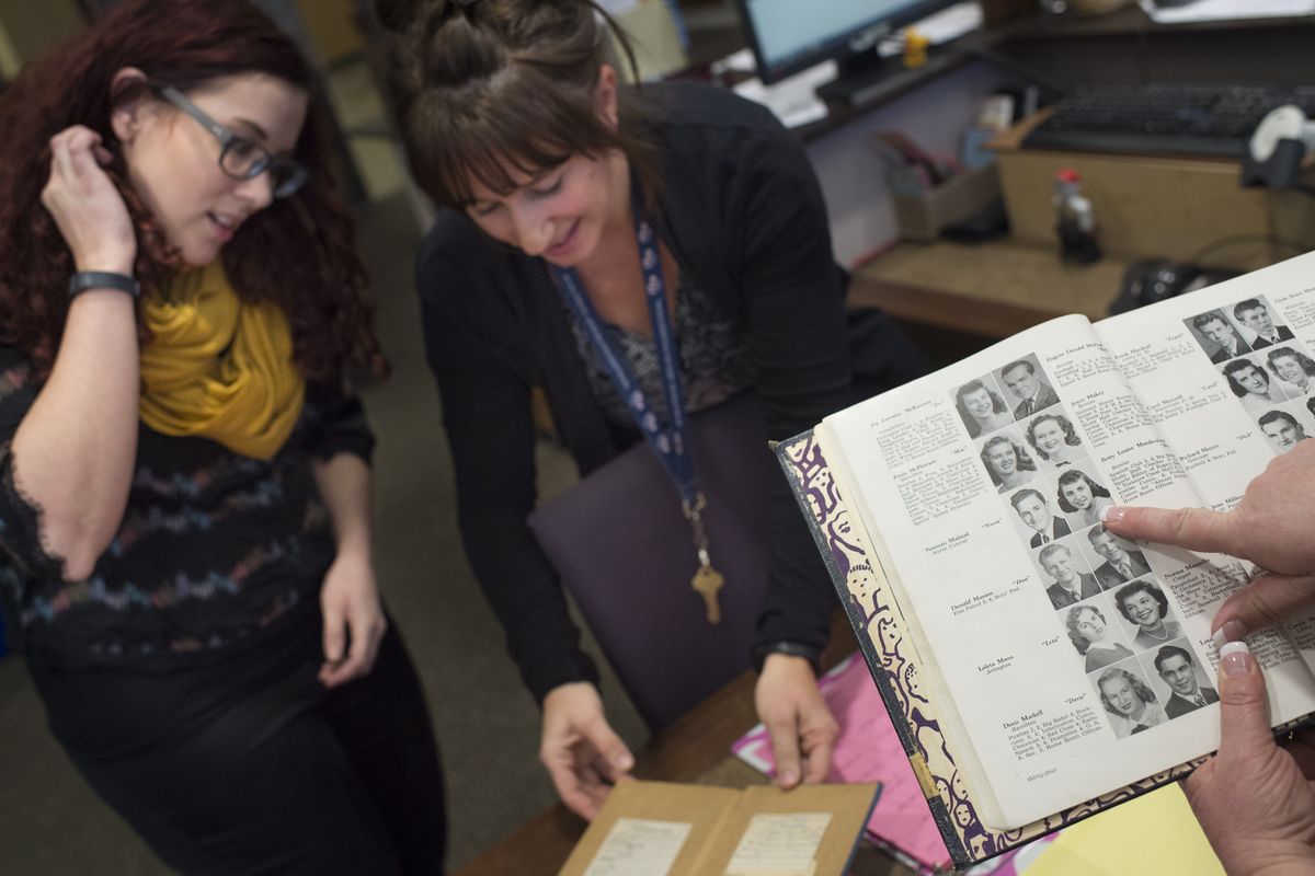 Rogers High School librarian Becky Huss, left, looks at a long-overdue copy of “Gone With the Wind” with school literacy coach Tracy Schumacher, center, as Principal Lori Wyborney finds the last student to check out the book, Betty Mandershied, in a 1949 yearbook late last month at the Spokane school. (Tyler Tjomsland)
