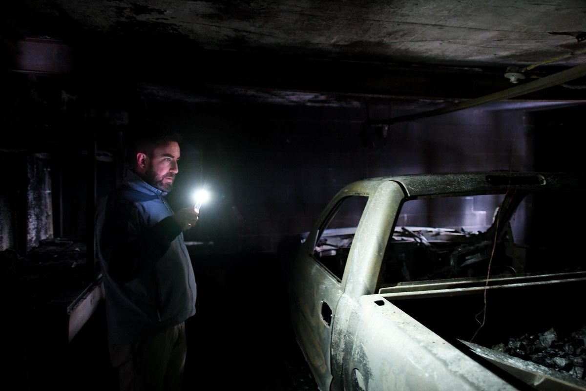 Lawyer Tim R. Fischer shines a light on a truck that he says squatters set on fire in the lower-level garage of City Councilwoman Karen Stratton
