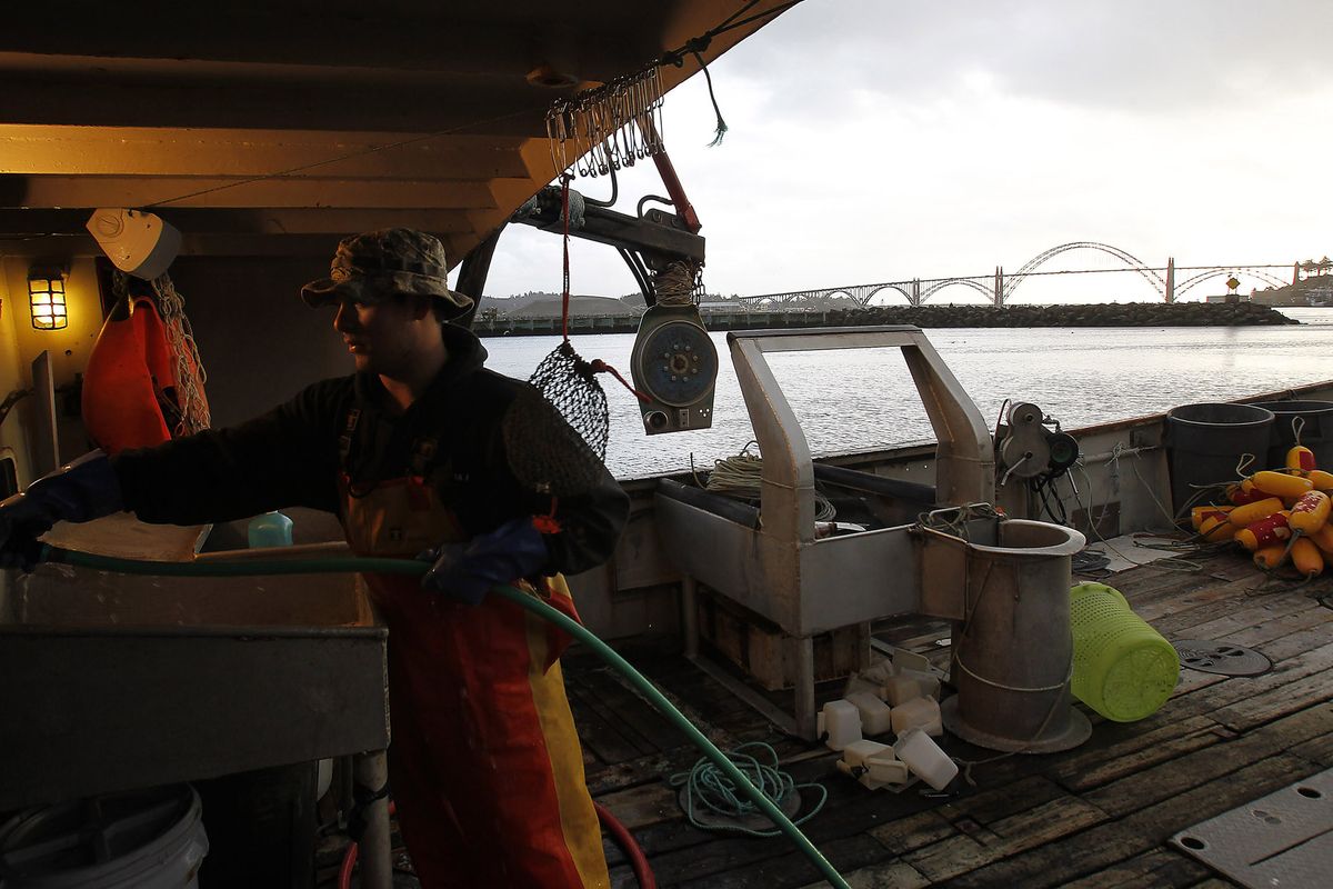 Brandon Yamanaka works on a boat on the Oregon Coast, where the economy relies on the crab harvest when tourism slows. (Kevin Clark)
