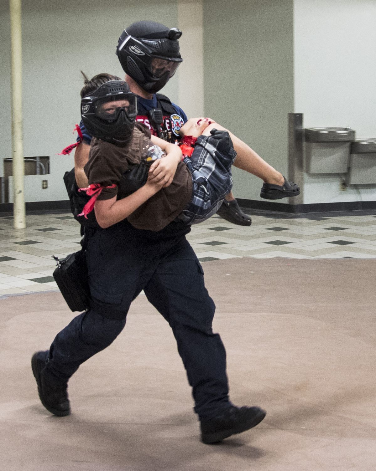 Cheney Fire Department firefighter Chris Munoz rescues Jerrod McMillin, 12, as part of the Joint Spokane Fire/Police Department Task Force training taking place in the basement of the NorthTown Mall on Thursday. This active shooter in a movie theater scenario included 12 victims in need of medical attention. (PHOTOS BY COLIN MULVANY)