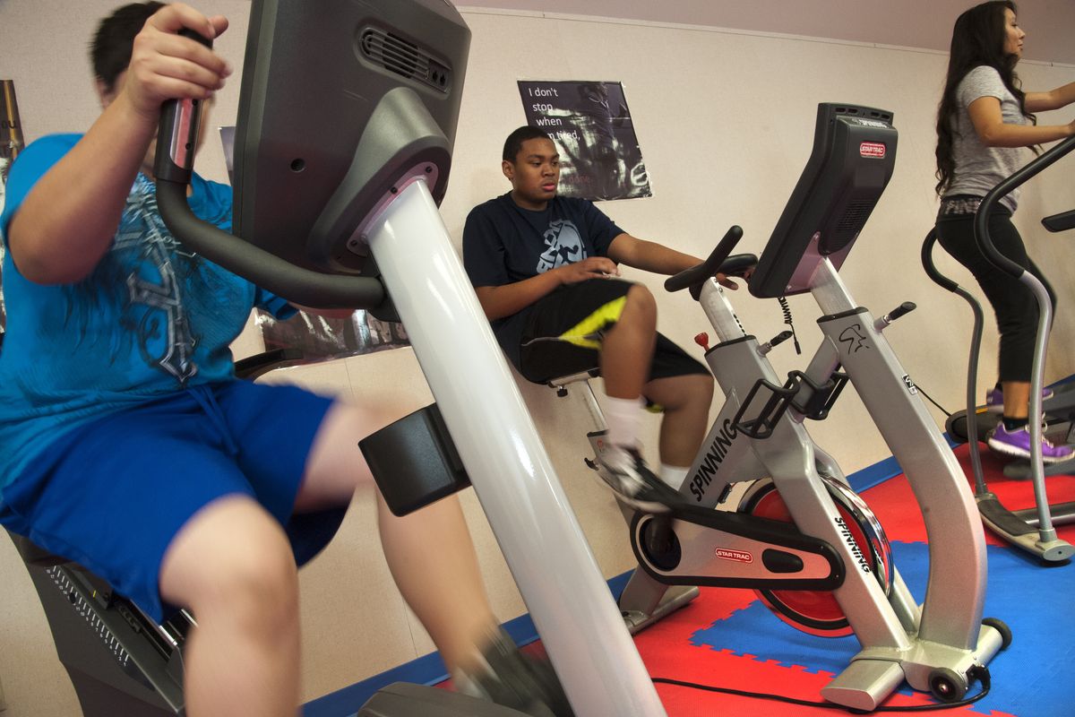 Cheney High School sophomore Travis Williams, 15, center, works out with other students in the school’s new cardio room last week. Williams has shed 45 pounds during the obesity intervention project in place in Cheney and used in various levels in six other districts. (Dan Pelle)