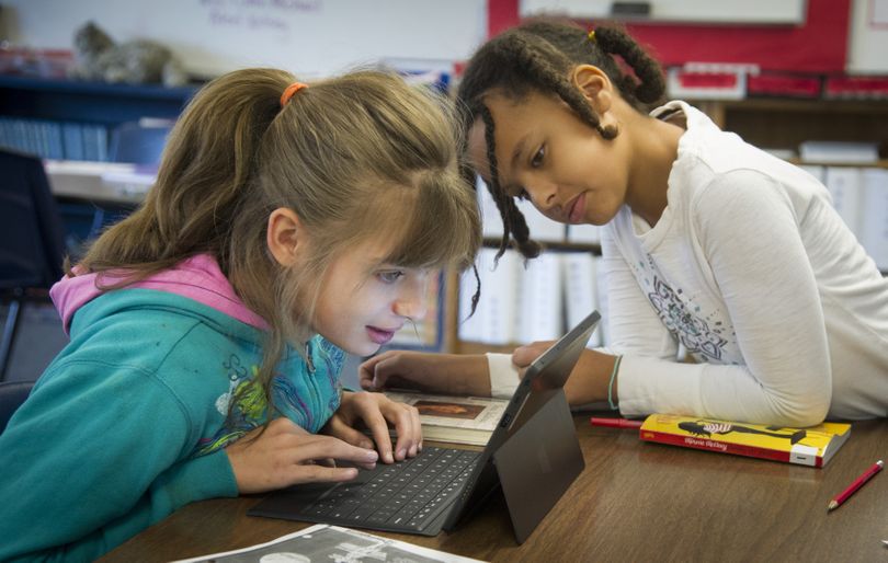 Saint George’s fifth-graders Erika Piotrowski, left, and Zadie Rigsby use a Microsoft Surface tablet while working together on a science fair project about the top 10 diseases of 1912. The school is in the process of integrating tablet computers into its curriculum. (Colin Mulvany)