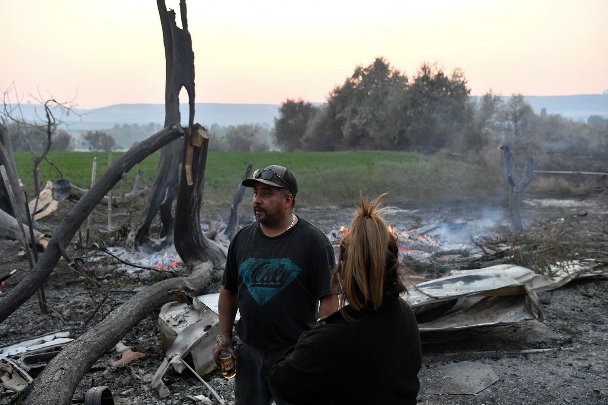 Omar Vega stands with a woman who asked to remain unidentified amid his destroyed homestead after the Pearl Hill Fire roared through on Tuesday near Monse, Wash. Vega said the trailer destroyed at this property was a total loss, but he has a place to stay.  (Tyler Tjomsland/The Spokesman-Review)