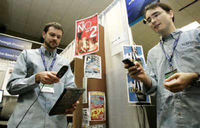 
Microsoft Corp. researchers Larry Zitnick, left, and Richard Hughes demonstrate Lincoln, Windows Mobile 5 phone technology that lets users take a cell phone photo of a DVD cover and then receive Amazon.com reviews, and other multi-media content relating to the DVD back on their phones.
 (Associated Press / The Spokesman-Review)