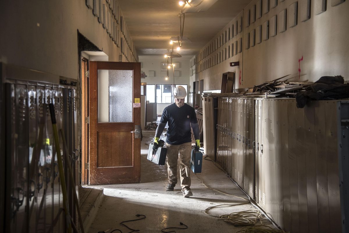 Adam Collins, of Yost Gallagher Construction, carries his tools down the second-floor hallway, Friday, Jan. 13, 2017, in the old Cheney High. The school is being renovated into student housing in a historic preservation project and many of the lockers will remain. (Dan Pelle / The Spokesman-Review)