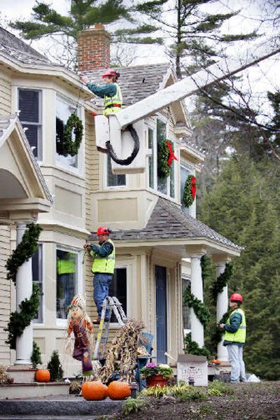 
Alex Peacock, in bucket, Tony Criscitelli, on ladder, and Adam Bendiksen, put up Christmas decorations on a house in Cape Elizabeth, Maine. Workers from a local tree service company stay busy in the fall installing Christmas lighting for homeowners who are either too harried or not inclined to climb ladders to do the job themselves. 
 (Associated Press / The Spokesman-Review)