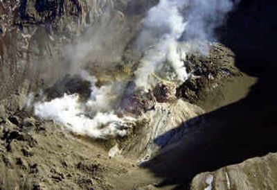 
Lava spills out onto the crater floor from rocky protuberances of new growth in Mount St. Helens on Thursday. At lower left is the volcano's old lava dome, lower right shows the top edge of the mountain and upper right behind the steaming new growth shows the blackened and cracked glacier.
 (Associated Press / The Spokesman-Review)