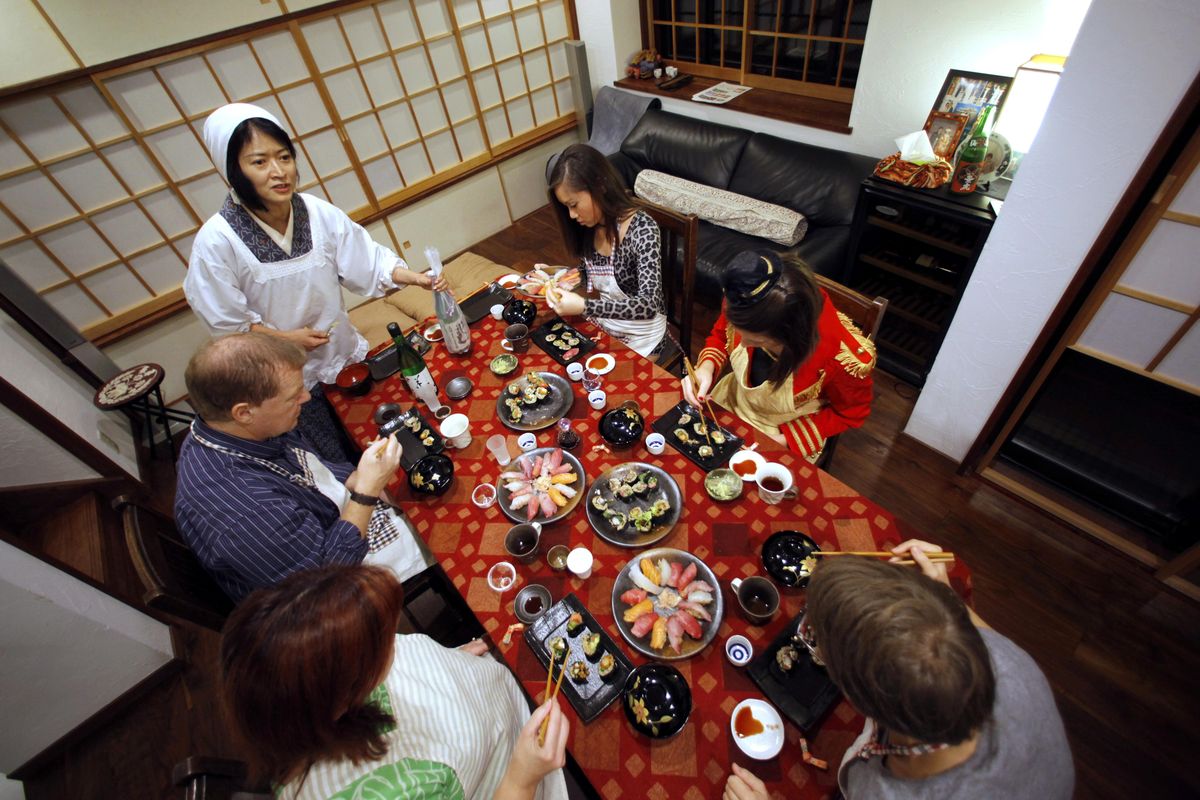 In this Oct. 31, 2015, photo, Shino Fukuyama, standing, teaches U.S. and Swiss tourists how to roll sushi as she hosts a dinner at her home in Tokyo. Tourists can learn about sushi, kimonos and enjoy dining with locals thanks to EatWith.com, which links travelers to chefs and talented home cooks around the world. (Shuji Kajiyama / AP)