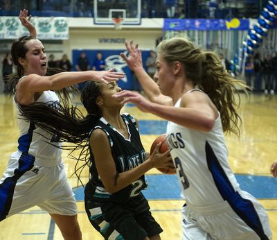 Coeur d’Alene’s Sydni Parker, left and Madison Sumner, right, double-team Lake City’s Whitney Meier. (Colin Mulvany)