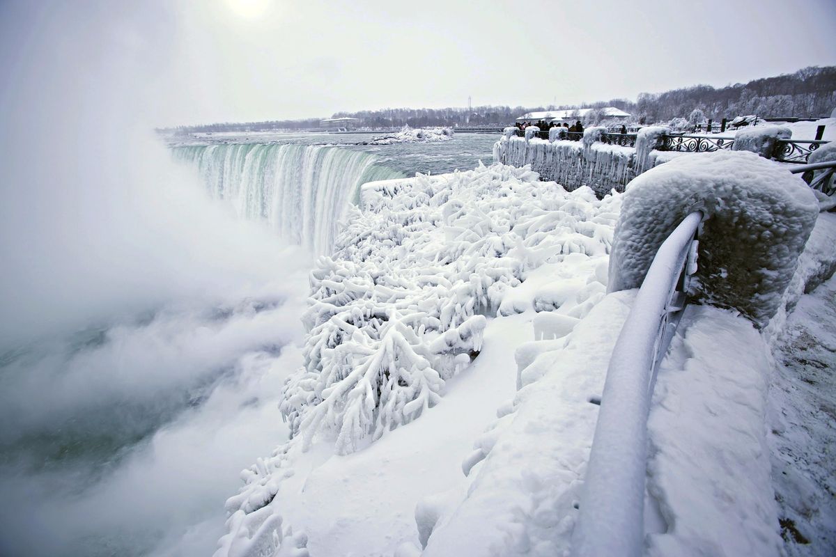 Visitors take photographs at the brink of the Horseshoe Falls in Niagara Falls, Ontario, as cold weather continues through much of the province on Friday, Dec. 29, 2017. (Aaron Lynett / AP)