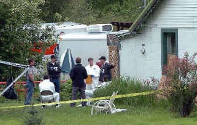 
Investigators confer Friday outside the home near Wolf Lodge Bay where a mother, her son and her boyfriend were beaten to death. The woman's 8- and 9-year-old children are still missing.
 (Jesse Tinsley / The Spokesman-Review)
