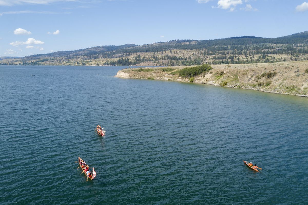 Two traditional cedar canoes and a smaller two-person canoe paddle near the confluence of the Spokane and Columbia Rivers Tuesday, June 15, 2021 on a trip to learn about their tribes’ history in the area while on a four-hour paddle up the Columbia. They met at nearby Fort Spokane, a military post founded in 1880, but it was also a school to educate Native kids, a process which was not always voluntary.  (Jesse Tinsley/The Spokesman-Review)
