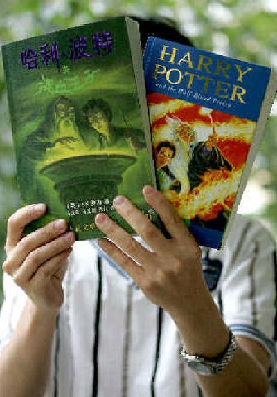 A Chinese man holds up Chinese and English paperback copies of