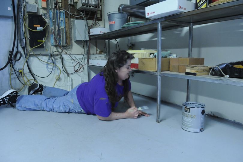 Maintenance worker Della Hedrick paints in the East Farms Elementary School boiler room that recently flooded because of the leaking roof. (J. Bart Rayniak)