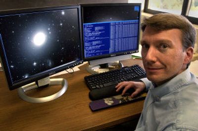 
Washington State University assistant professor John Blakeslee sits in front of his research images of galaxies. 
 (Brian Immel / The Spokesman-Review)