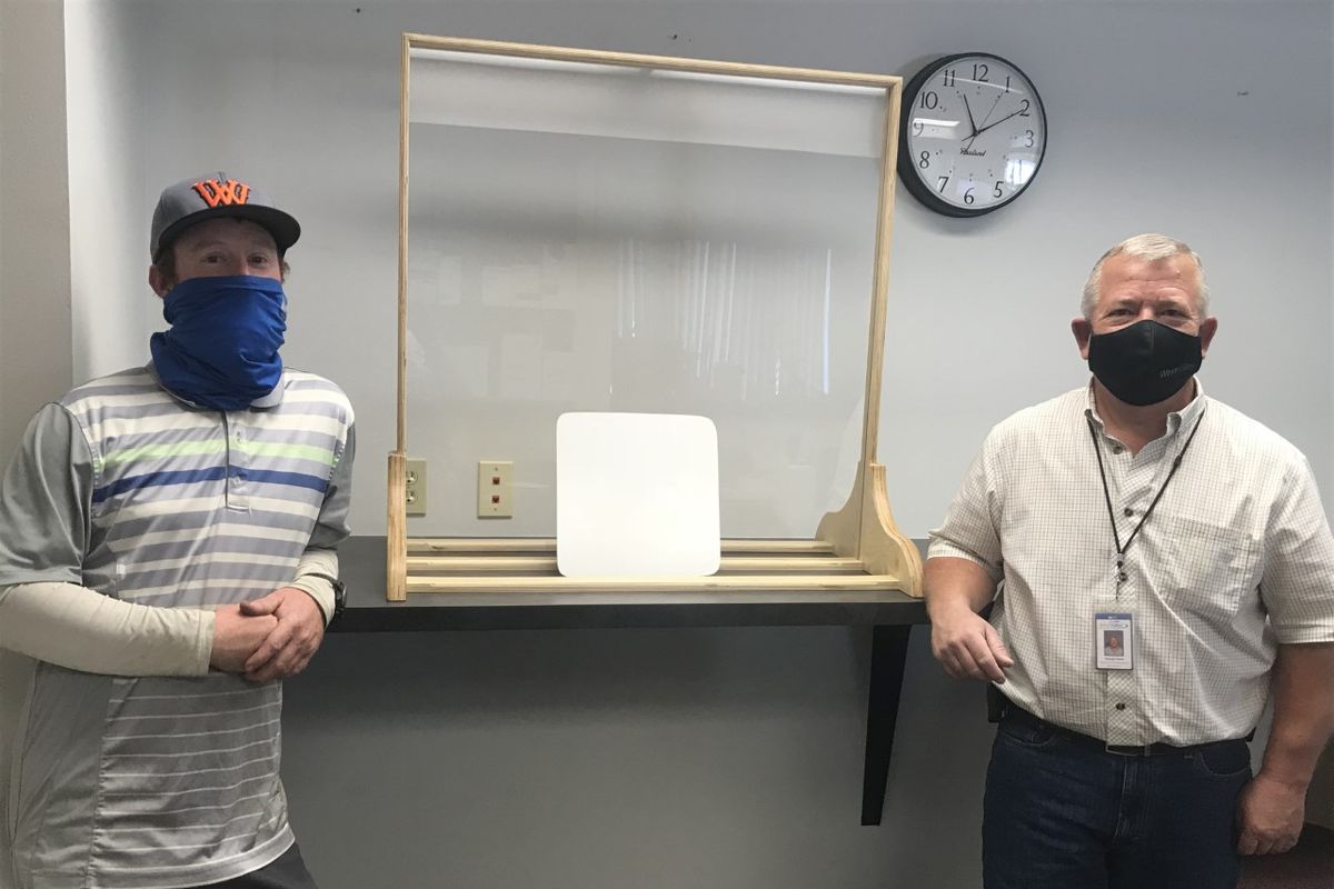 West Valley School District maintenance grounds employee Sam Bachman, left, and George Castor, maintenance and custodial director, are shown with one of the sneeze guard frames and whiteboards they made.  (Nina Culver/For The Spokesman-Review)