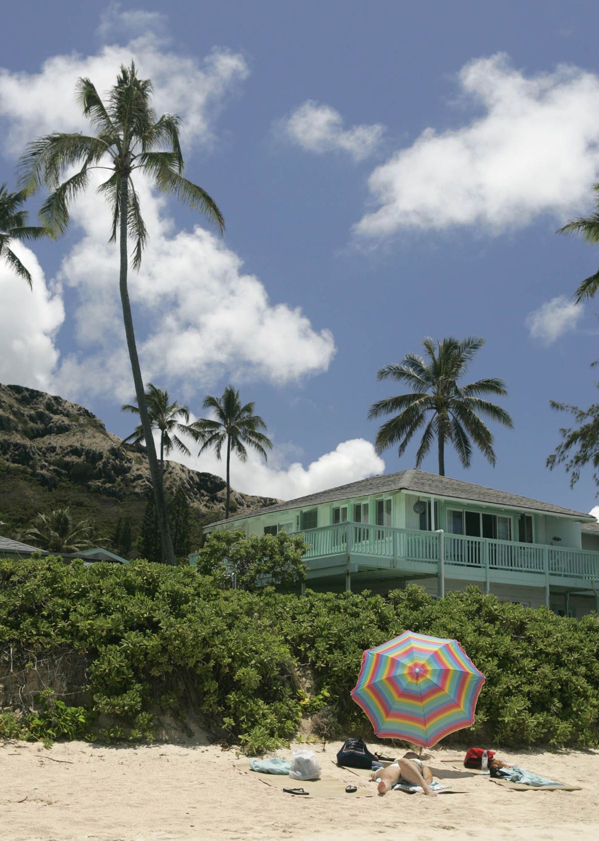 A sunbather lounges on Lanikai Beach in front of million dollar-view homes in Lanikai, Hawaii. (Marco Garcia / The Spokesman-Review)