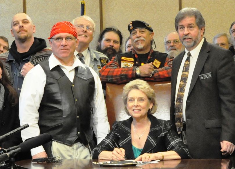 Supporters of a bill, including a biker behind the governor who is wearing the patches of the Bandidos motorcycle club and a 1-percenter patch on his vest, smile for the camera after Chris Gregoire signs a bill banning motorcycle profiling (Jim Camden/The Spokesman-Review)