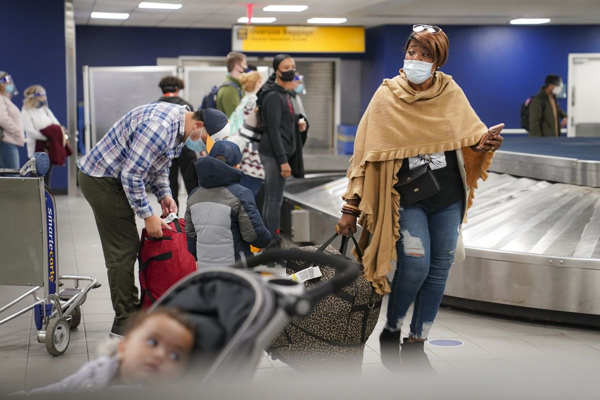 Travelers wearing masks to prevent the spread of COVID-19 prepare to leave the Terminal C baggage claim area at LaGuardia Airport in New York on Nov. 25, in the Queens borough of New York. Millions of Americans are taking to the skies and hitting the road ahead of Thanksgiving at the risk of pouring gasoline on the coronavirus fire. They are disregarding increasingly dire warnings that they stay home and limit their holiday gatherings to members of their own household. (AP Photo/John Minchillo)  (John Minchillo / Associated Press)