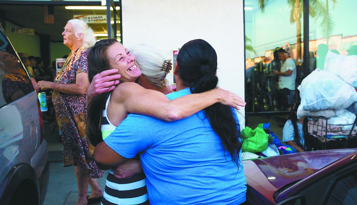 Jeanne Strickler, left, who is homeless, hugs her friends outside a laundromat before doing their laundry for free during a Laundry Love event. (Associated Press)