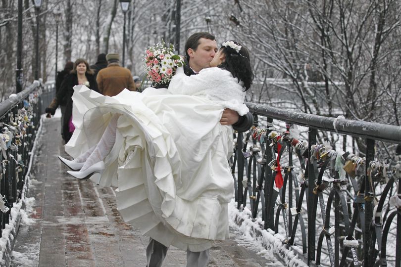 Newly wedded couple Sergiy, left, and Irina kiss as they cross the Bridge of Love in Kiev, Ukraine, Friday, Jan. 21, 2011. Loving couples express their feelings by putting padlocks and ribbons on the railings, as well as painting their names and hearts everywhere. (Efrem Lukatsky / Associated Press)