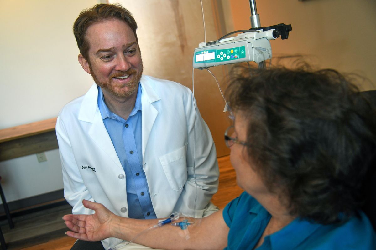 Dr. Jason Aldred of Inland Northwest Research visits with a patient receiving an infusion trial for Parkinson’s disease on Tuesday19. (Dan Pelle / The Spokesman-Review)