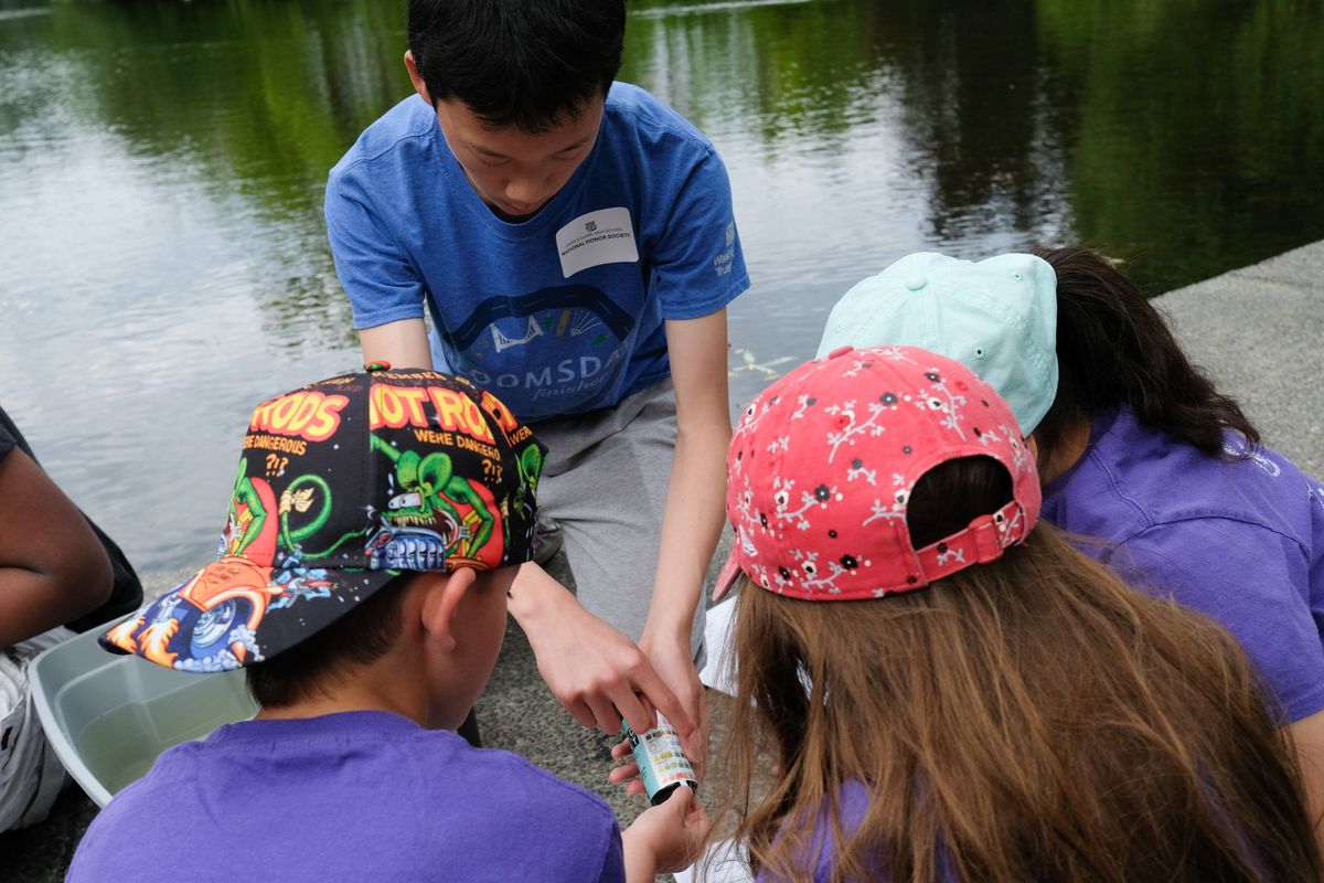 Tim Li, a sophomore at Lewis and Clark, demonstrates to Roosevelt Elementary students how to test pH levels of water from Mirror Pond during a field trip Thursday. On their Manito Park field trip, students engaged in six STEAM learning stations and took notes, logging their observations in journals.  (Tyler Tjomsland/The Spokesman-Review)