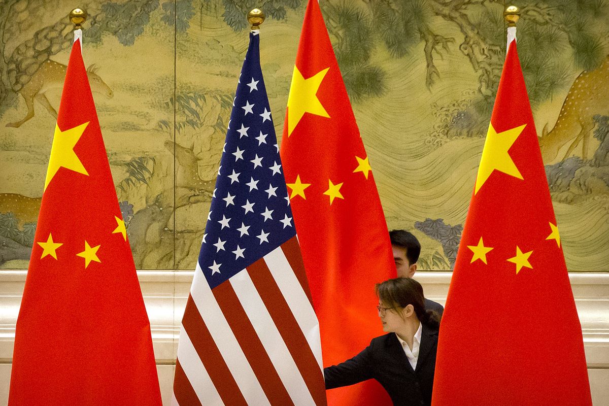 FILE - In this Feb. 14, 2019, file photo, Chinese staffers adjust the U.S. and Chinese flags before the opening session of trade negotiations between U.S. and Chinese trade representatives at the Diaoyutai State Guesthouse in Beijing. In a relationship as fraught as America