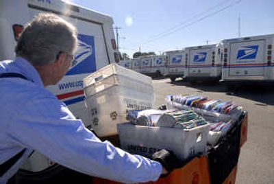 Ernie Turner rolls a cart full of sorted mail to his truck before beginning his route. 
 (Holly Pickett / The Spokesman-Review)